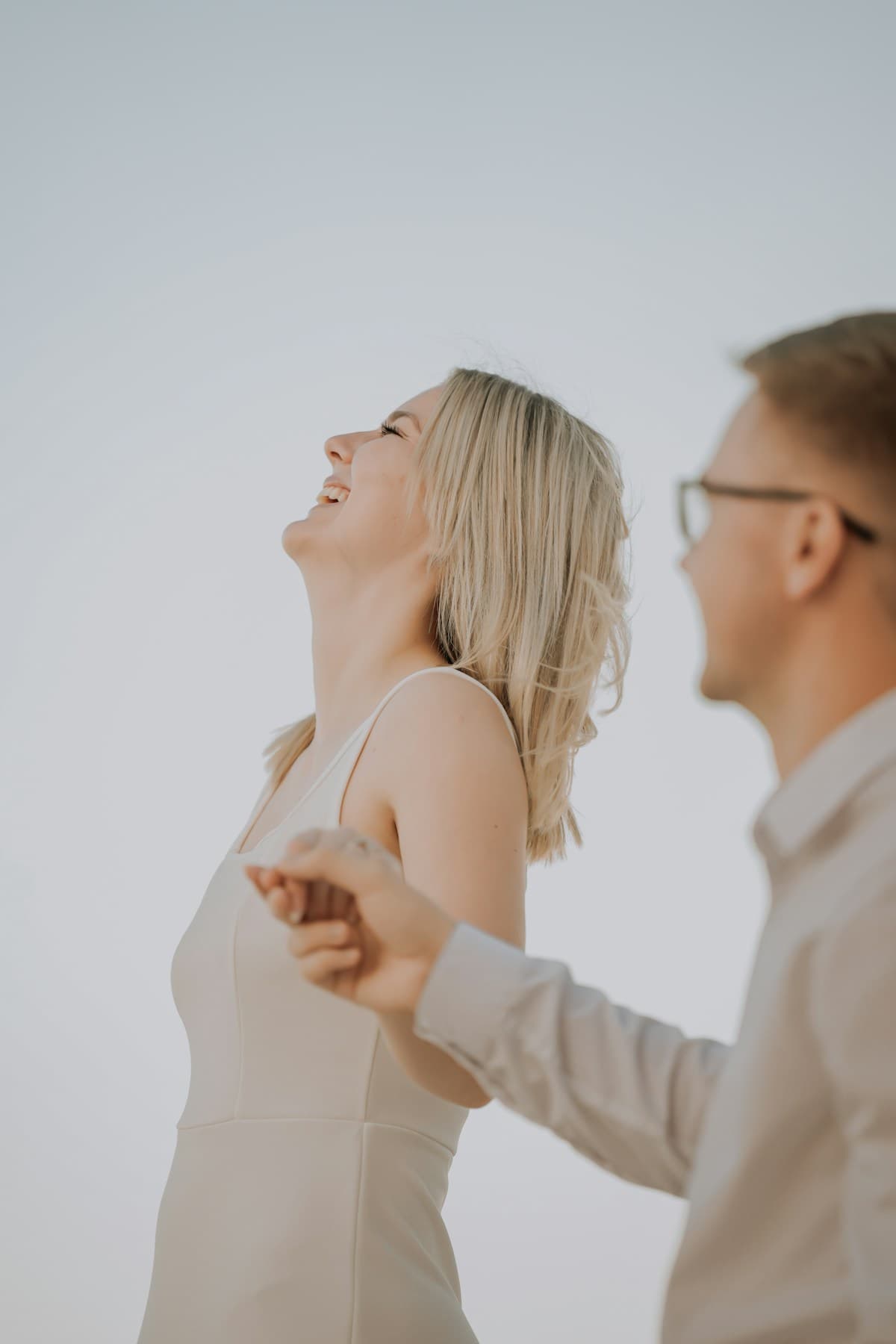 A joyful couple laughing and holding hands outdoors